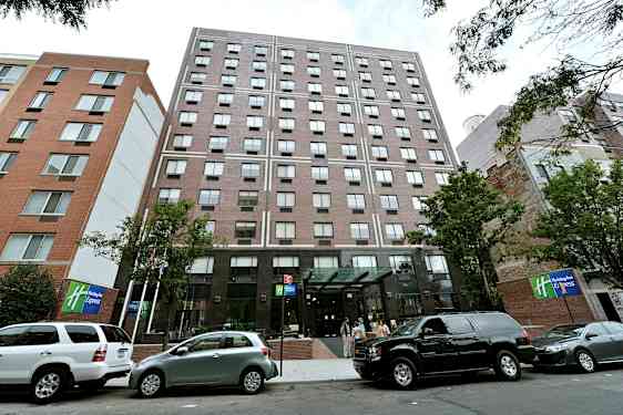 Kerrostalo, jossa lasiovi ja parkkeerattuja autoja edessä. (Tekoälyn luoma teksti)