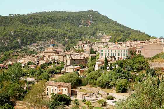 Kuva vuoristokylästä, jossa on useita kivitaloja vehreän kasvillisuuden ympäröimänä. (Tekoälyn luoma teksti)