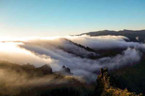 Pilvet liikkuvat vuoriston yllä auringonnousun tai -laskun aikaan. (Tekoälyn luoma teksti)