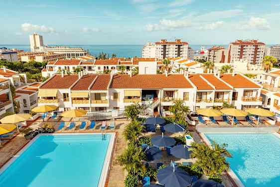 Huoneistojen rakennukset punaisilla katoilla, allasalueet ja meri taustalla. (Tekoälyn luoma teksti)