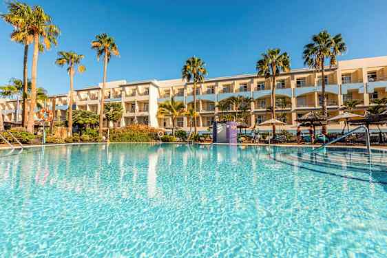 Ulkoallas, jota ympäröivät palmut ja taustalla hotelli. (Tekoälyn luoma teksti)