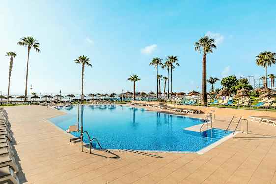 Ulkouima-allas, jota ympäröivät aurinkotuolit ja palmupuut kirkkaan sinisen taivaan alla. (Tekoälyn luoma teksti)