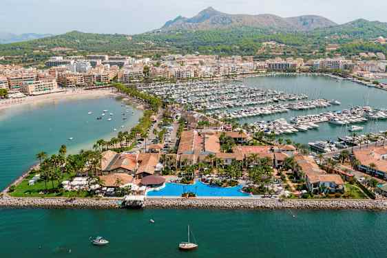 Ilmakuva satama-alueesta, jossa veneitä ja ympäröiviä rakennuksia. (Tekoälyn luoma teksti)