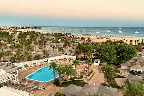 Ilmakuva hotellialueesta, jossa uima-allas, palmuja ja ranta taustalla. (Tekoälyn luoma teksti)