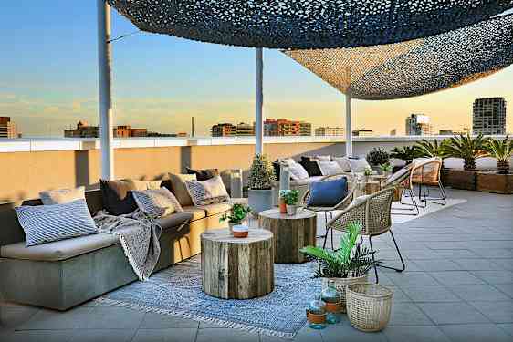 Kuvassa on kattoterassi, jossa on istuimia, pöytiä ja koreja koristeltuina kasveilla ja tyynyillä. (Tekoälyn luoma teksti)