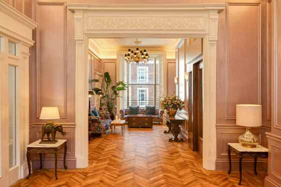 Tyylikäs huone, jossa puulattia, klassiset huonekalut ja kristallikruunu. (Tekoälyn luoma teksti)