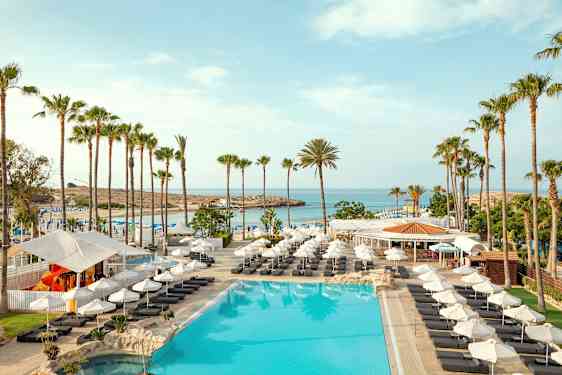 Kuva altaasta, jossa on aurinkotuoleja, aurinko- ja palmuja rannalla. (Tekoälyn luoma teksti)