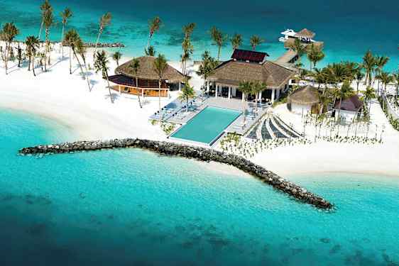 Ilmakuva trooppisesta lomakohteesta meren rannalla, jossa on uima-allas, valkoiset rannat ja palmut. (Tekoälyn luoma teksti)