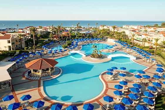 Ulkouima-allas, jota ympäröivät aurinkotuolit ja aurinkovarjot, taustalla hotellirakennuksia ja meri. (Tekoälyn luoma teksti)