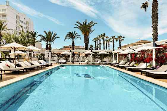 Ulkouima-allas, jota ympäröivät aurinkotuolit ja aurinkovarjot, taustalla palmuja. (Tekoälyn luoma teksti)