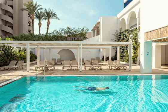 Ulkouima-allas, jossa on aurinkotuoleja vieressä ja henkilö uimassa vedessä. (Tekoälyn luoma teksti)