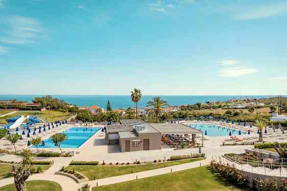 Hotellialue, jossa on kaksi uima-allasta, aurinkotuoleja ja merinäköala. (Tekoälyn luoma teksti)