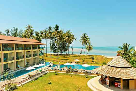 Lomakeskus, jossa on uima-allas, aurinkotuoleja ja aurinkovarjoja, lähellä palmuja sisältävää rantaa. (Tekoälyn luoma teksti)