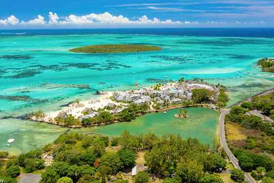 Ilmakuva lomakohteesta rannalla, turkoosin veden ja vehreyden ympäröimänä. (Tekoälyn luoma teksti)