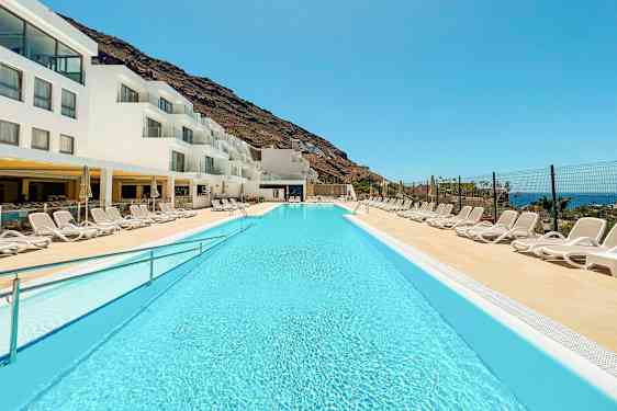 Hotellin uima-allas, valkoisia rakennuksia ja aurinkotuoleja. (Tekoälyn luoma teksti)