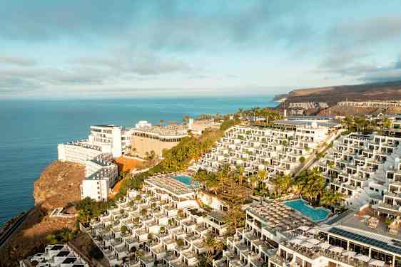 Hotellikompleksi kalliolla, jossa on uima-altaita ja merinäköala. (Tekoälyn luoma teksti)