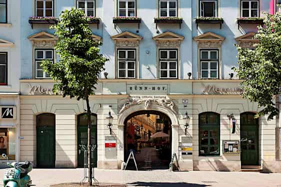 Rakennus, jossa on ikkunoita, kaariportti ja kukkalaatikot ikkunoiden vieressä. (Tekoälyn luoma teksti)