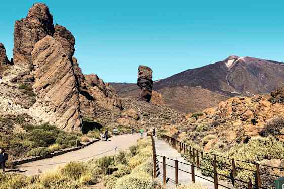 Kivimuodostelma, jonka ohi kulkee kävelytie, ja taustalla vuoria. (Tekoälyn luoma teksti)