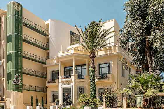 Hotellirakennuksen kuva palmujen ympäröimänä. (Tekoälyn luoma teksti)