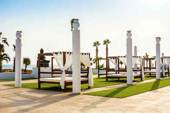 Ulkotila katossänkyineen ja patsaineen meren rannalla. (Tekoälyn luoma teksti)