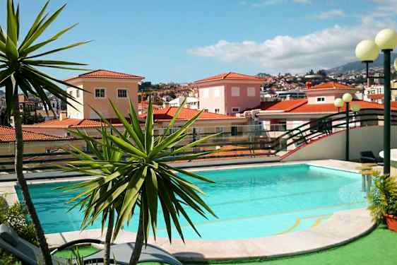 Uima-allas, jota ympäröi vehreys, ja taustalla on punatiilikattoisia taloja. (Tekoälyn luoma teksti)