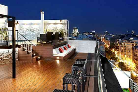 Kattoikerassilla valaistus, ulkokalusteet ja istutuksia, näkymä yli kaupungin illalla. (Tekoälyn luoma teksti)