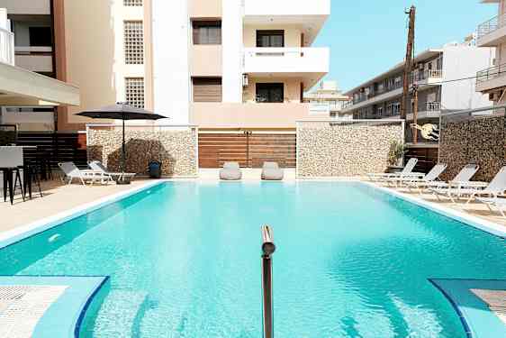 Ulkoallas, jota ympäröivät aurinkotuolit ja rakennukset. (Tekoälyn luoma teksti)