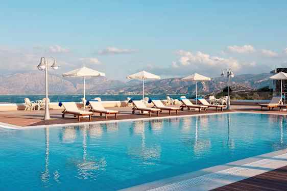 Aurinkotuolit ja aurinkovarjot ulkoaltaalla näkymällä vuorille ja merelle. (Tekoälyn luoma teksti)