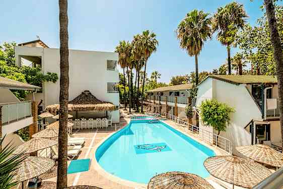 Ulkoallas, jota ympäröivät valkoiset rakennukset ja palmut. (Tekoälyn luoma teksti)