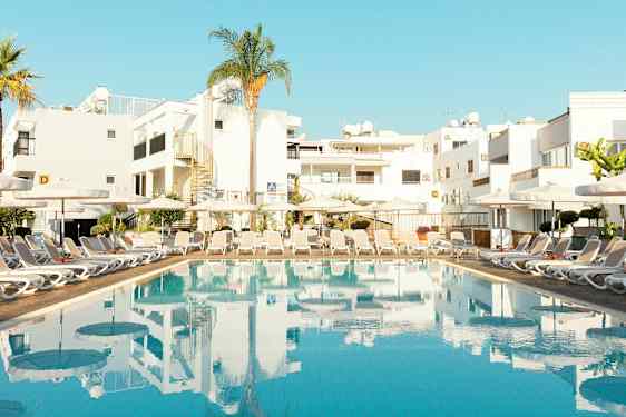 Uima-allas aurinkotuoleilla ja rakennuksia taustalla. (Tekoälyn luoma teksti)