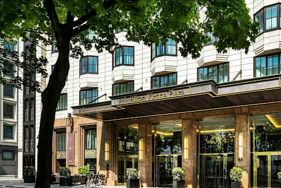 Hotellirakennus, jossa on tyylikäs sisäänkäynti, puiden ympäröimänä. (Tekoälyn luoma teksti)