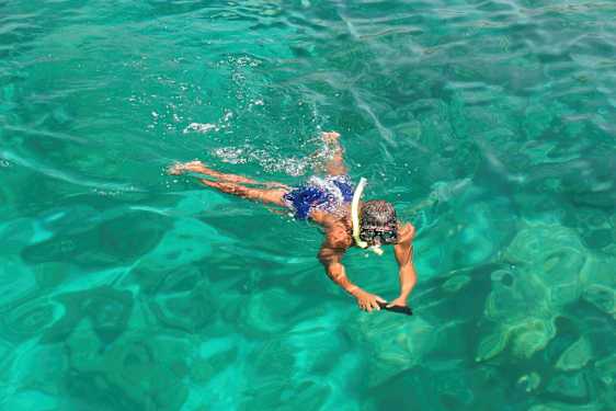 Henkilö ui kirkkaassa vedessä snorklausvarusteilla. (Tekoälyn luoma teksti)