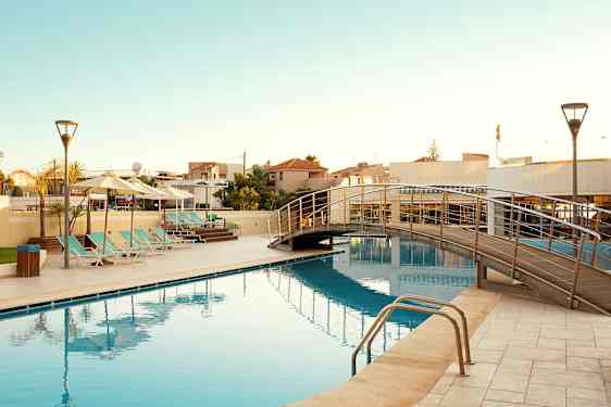 Ulkouima-allas, jossa on aurinkotuoleja ja kävelysilta veden yli. (Tekoälyn luoma teksti)