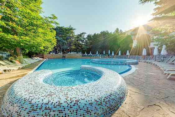 Ulkoallas, jossa aurinkotuoleja ja puita taustalla. (Tekoälyn luoma teksti)