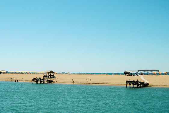 Ranta meren äärellä aurinkotuoleilla ja aurinkovarjoilla sekä puulaituri. (Tekoälyn luoma teksti)