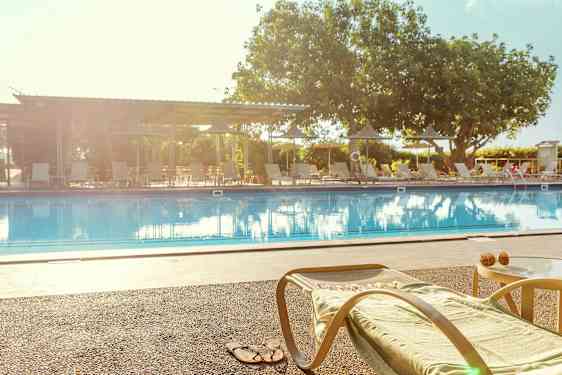 Lepotuoli ja pöytä uima-altaan reunalla. (Tekoälyn luoma teksti)