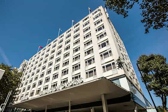 Kerrostalo, jossa näkyvät ikkunat ja lippuja katolla. (Tekoälyn luoma teksti)