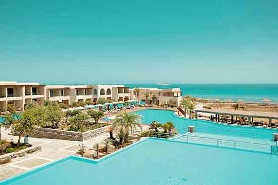 Lomakeskus, jossa on uima-allasalue, trooppisia kasveja ympärillä ja näkymä merelle. (Tekoälyn luoma teksti)