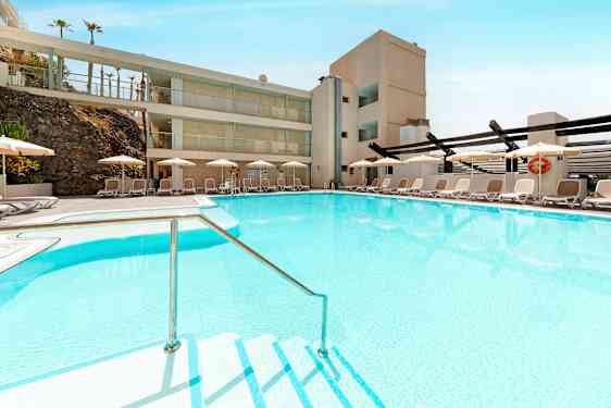 Uima-allas, jossa kirkasta sinistä vettä, ympäröitynä aurinkotuoleilla ja aurinkovarjoilla. (Tekoälyn luoma teksti)