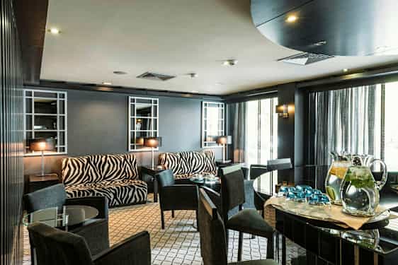 Huone, jossa seeprakuviollisia huonekaluja ja lasipöytiä. (Tekoälyn luoma teksti)