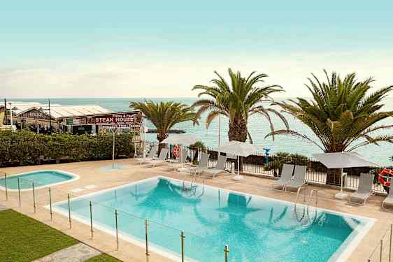 Uima-allasalue aurinkotuoleilla ja aurinkovarjoilla rannan vieressä. (Tekoälyn luoma teksti)