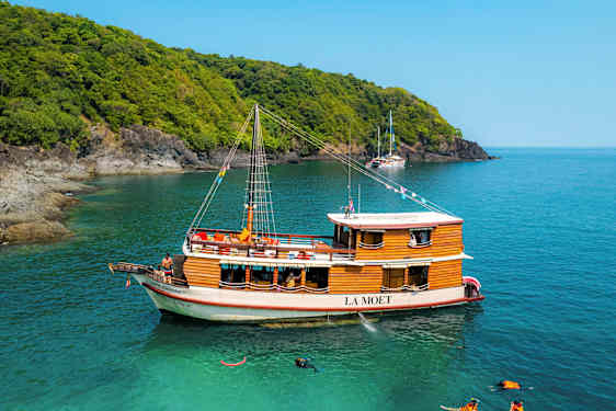 Puinen vene nimeltä La Moet on kiinnitetty turkoosiin veteen lähellä metsän reunustamaa rantaa. (Tekoälyn luoma teksti)