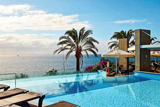 Kuvassa on infinity-allas merinäkymän edessä palmuja. (Tekoälyn luoma teksti)