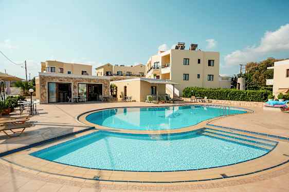 Kuva, jossa näkyy ulkouima-allas, jota ympäröivät aurinkotuolit ja taustalla on rakennuksia. (Tekoälyn luoma teksti)