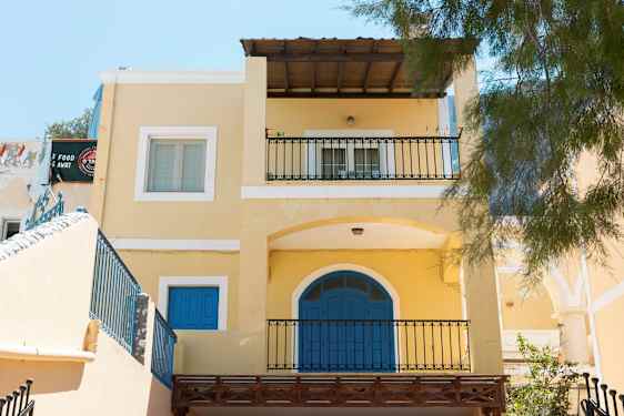 Keltainen talo sinisillä ovilla ja parvekkeilla. (Tekoälyn luoma teksti)