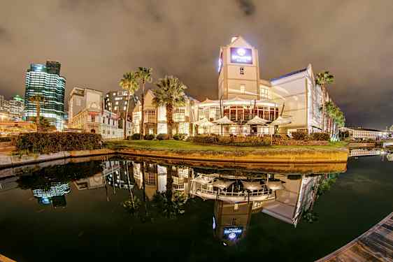 Hotelli ja rakennuksia kanavan varrella yöllä, heijastuksia vedessä. (Tekoälyn luoma teksti)