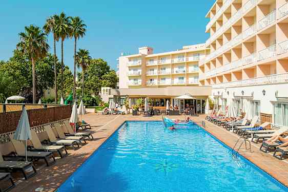 Hotellirakennus näkyy ulkouima-altaan vieressä, ympärillä aurinkotuoleja ja aurinkovarjoja. (Tekoälyn luoma teksti)