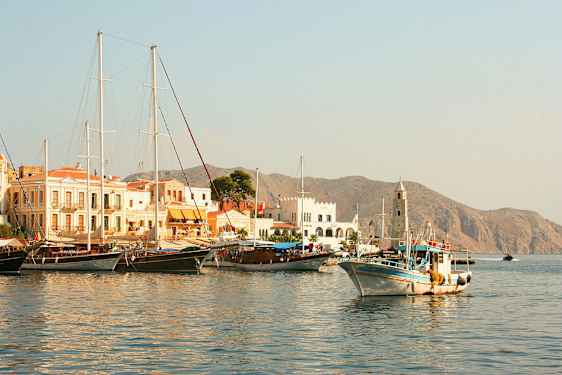 Satama, jossa on veneitä ja rakennuksia, taustalla näkyy vuoria. (Tekoälyn luoma teksti)