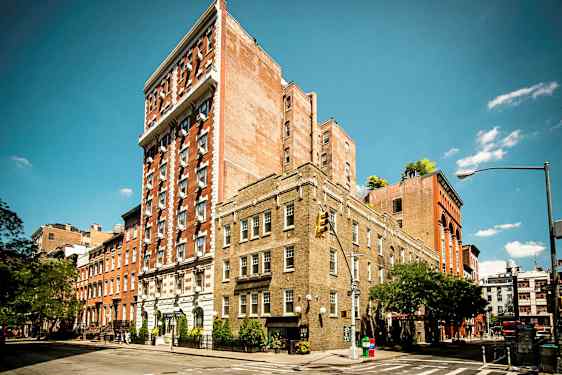 Useita tiilirakennuksia kadunkulmassa kirkkaan sinisen taivaan alla. (Tekoälyn luoma teksti)