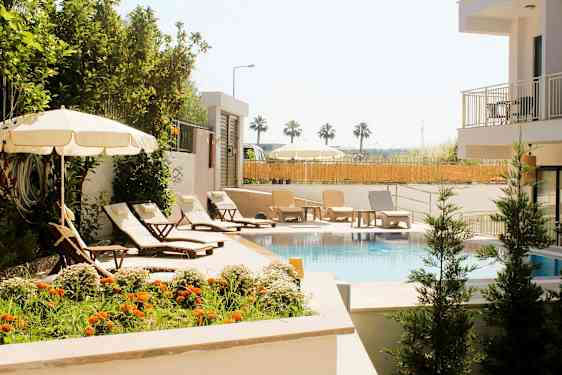 Uima-allas, jonka ympärillä on aurinkotuoleja, varjoja ja vihreää kasvillisuutta. (Tekoälyn luoma teksti)